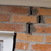 A brick wall displaying stair-step cracks and messy tuckpointing on a Nicholasville home