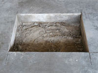 Creating the hole in the garage slab floor during the wall anchor installation in Wilmore.