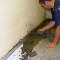 A basement waterproofer installing a perimeter drain system in Cynthiana