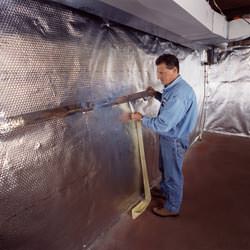Installation of a radiant heat and vapor barrier on a basement wall in Hazard